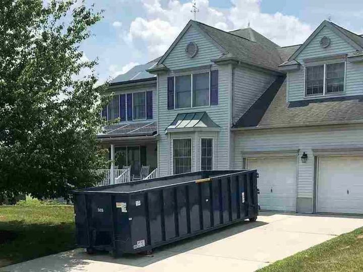 Roll-off dumpster in the driveway of a home (Estate Clean Out Services) by Moving Pros CLE