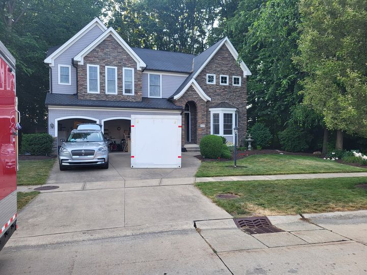 Two-story stone and siding home with a driveway (Onsite Moving Services) by Moving Pros CLE